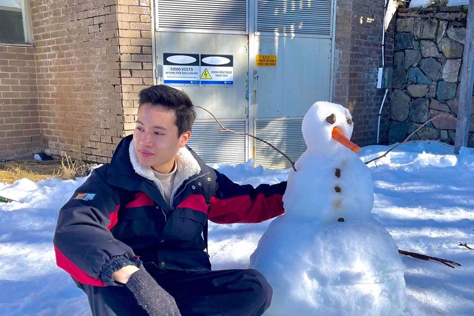 a boy posing next to a snowman
