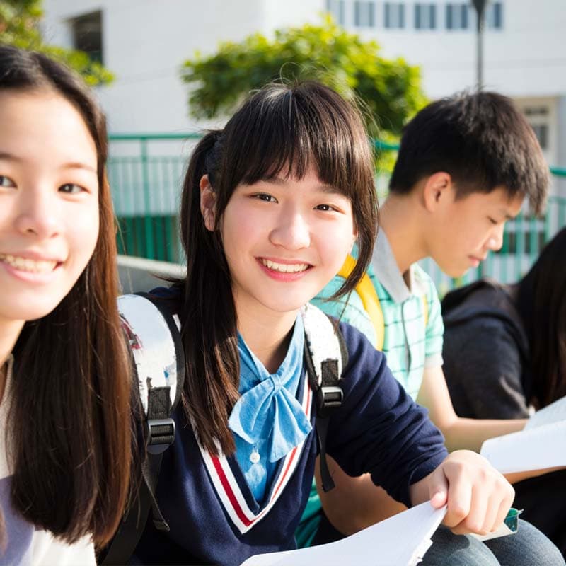 three highschool students smiling while looking into the camera