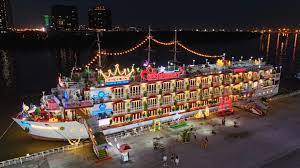 Indochina Queen Cruises’ multi-deck river boat brightly lit at night while docked, prepared to host a dinner cruise along the waterfront.