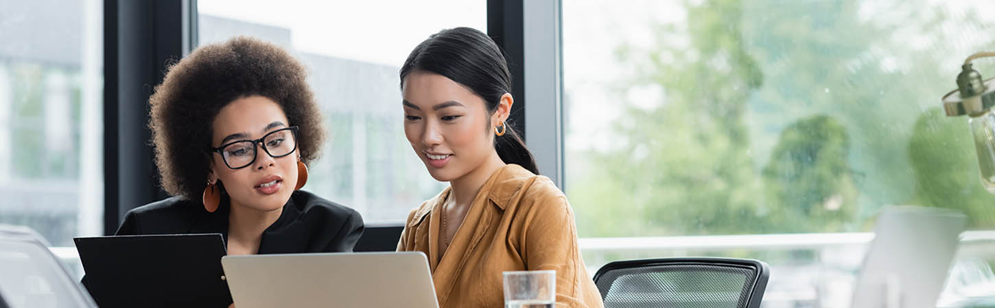 asian and african american managers looking at laptop while working in office, banner