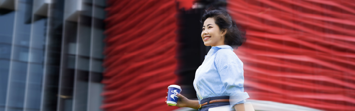 A Business postgraduate holding a cup and the RMIT Saigon South builiding in the background.