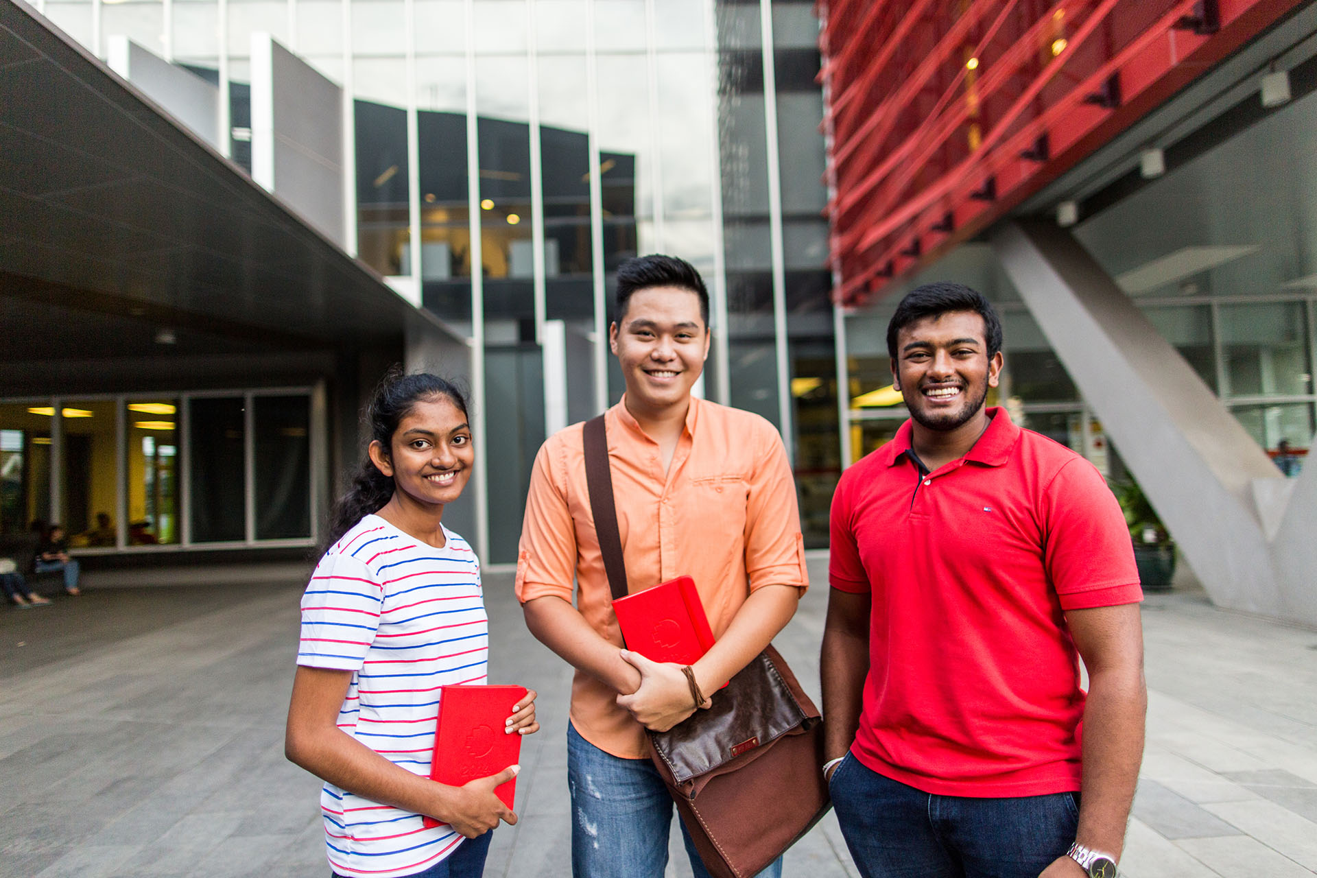 A group of three international students smiling at the camera