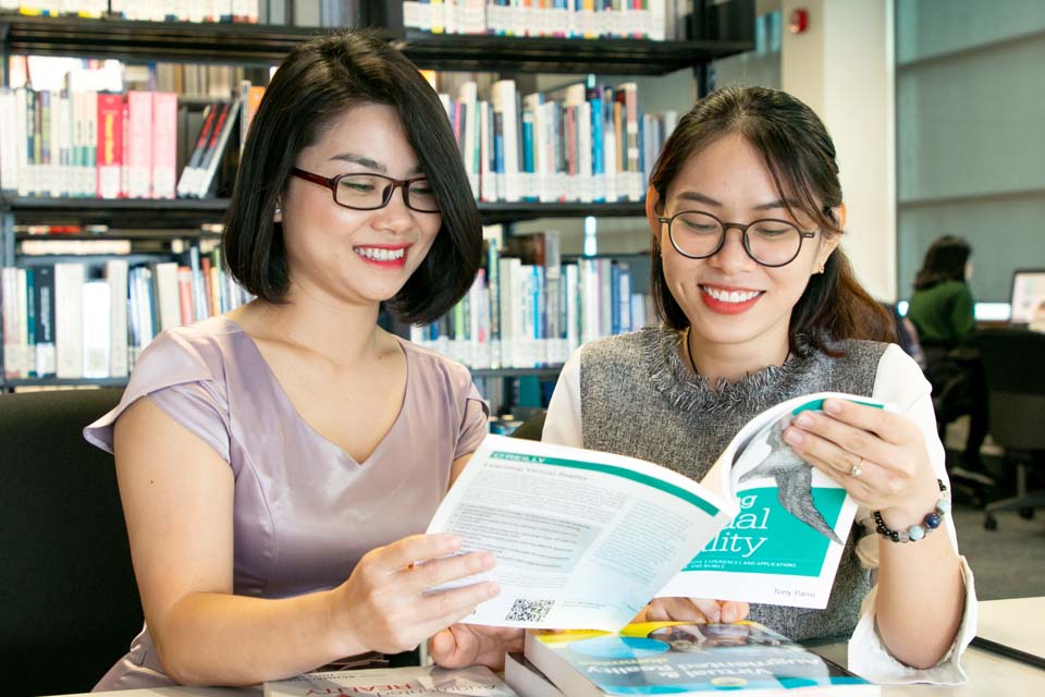 two women holding book and smiling