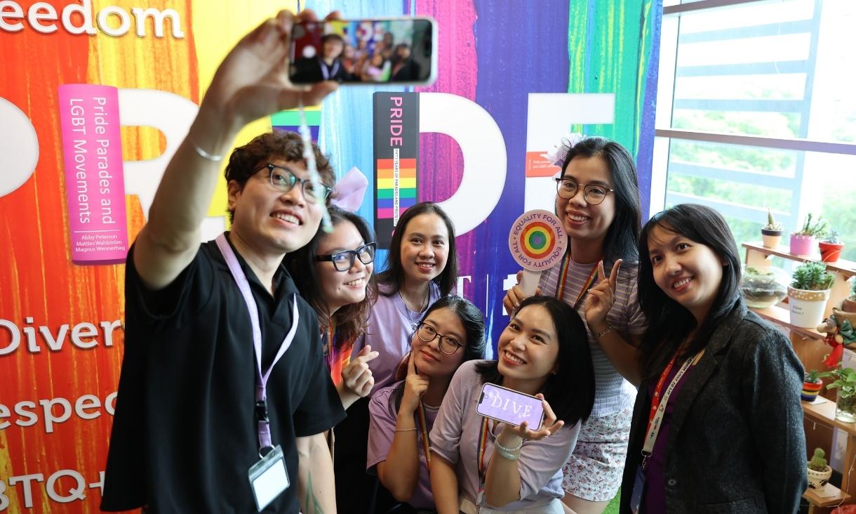 The photo of a group of 7 people doing a selfie together in front of a backdrop