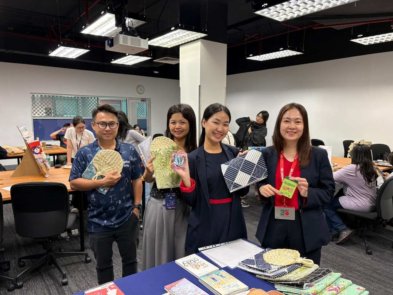 Group of people holding up items and smiling around a conference table at an indoor event.