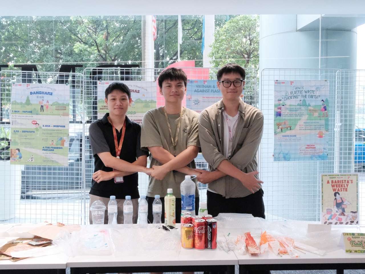 Four people standing behind a table with drinks and snacks, posing for a photo at an indoor event.