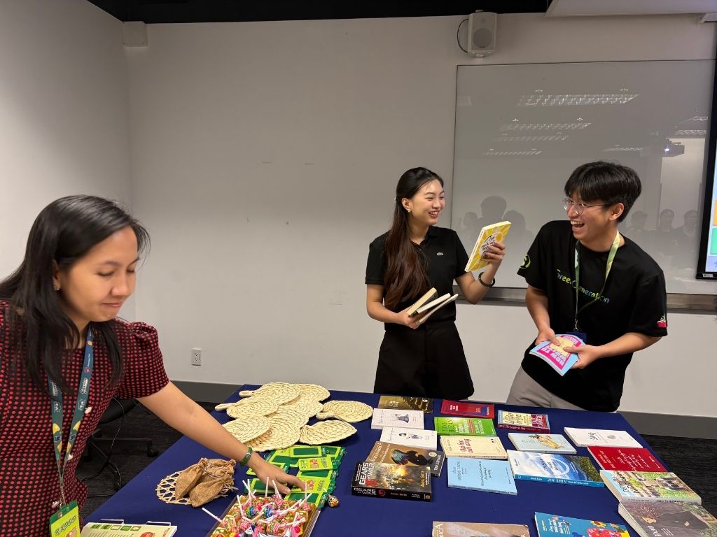Two people standing at a table displaying books, snacks, and event materials.