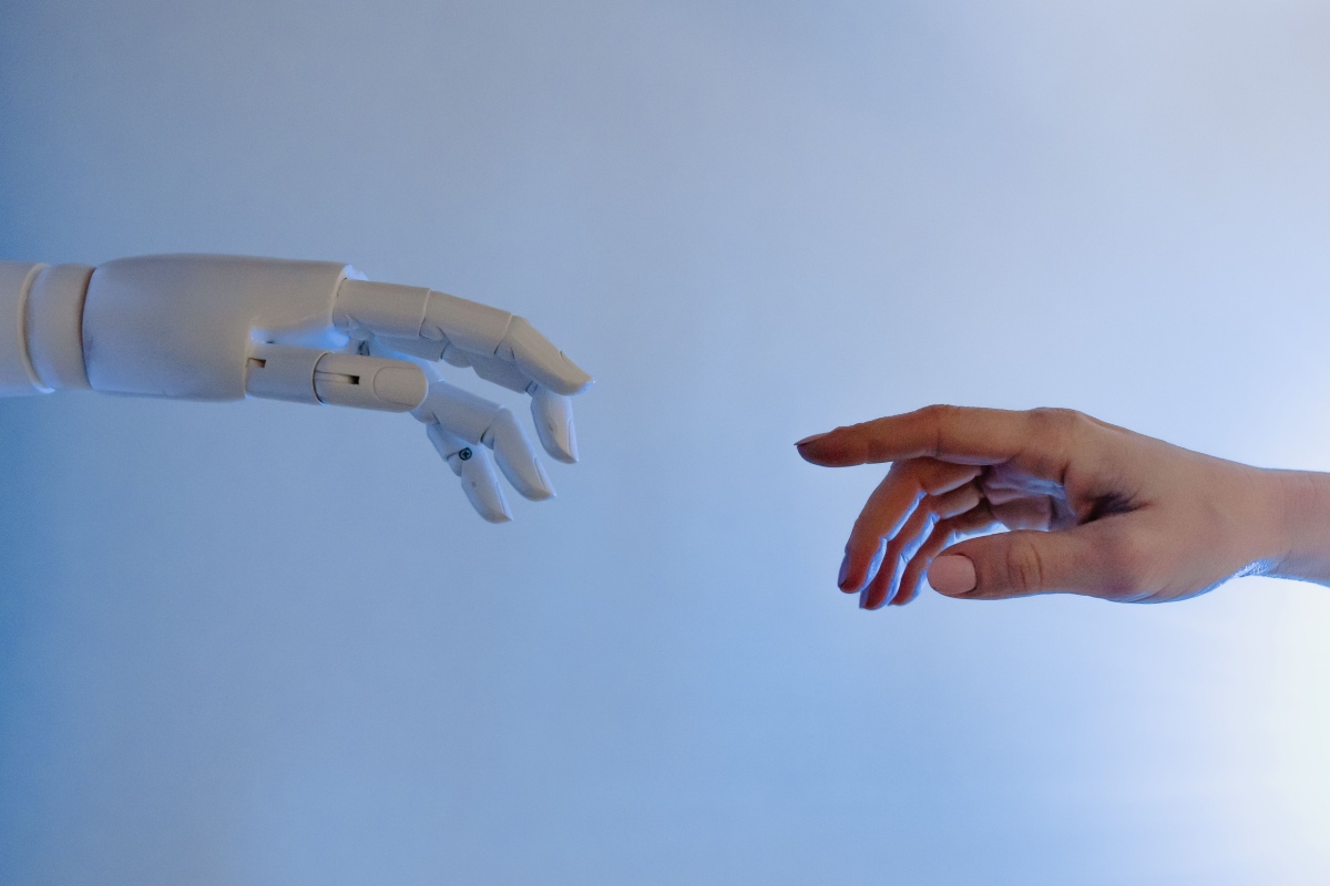 A robot hand and a human hand reaching toward each other