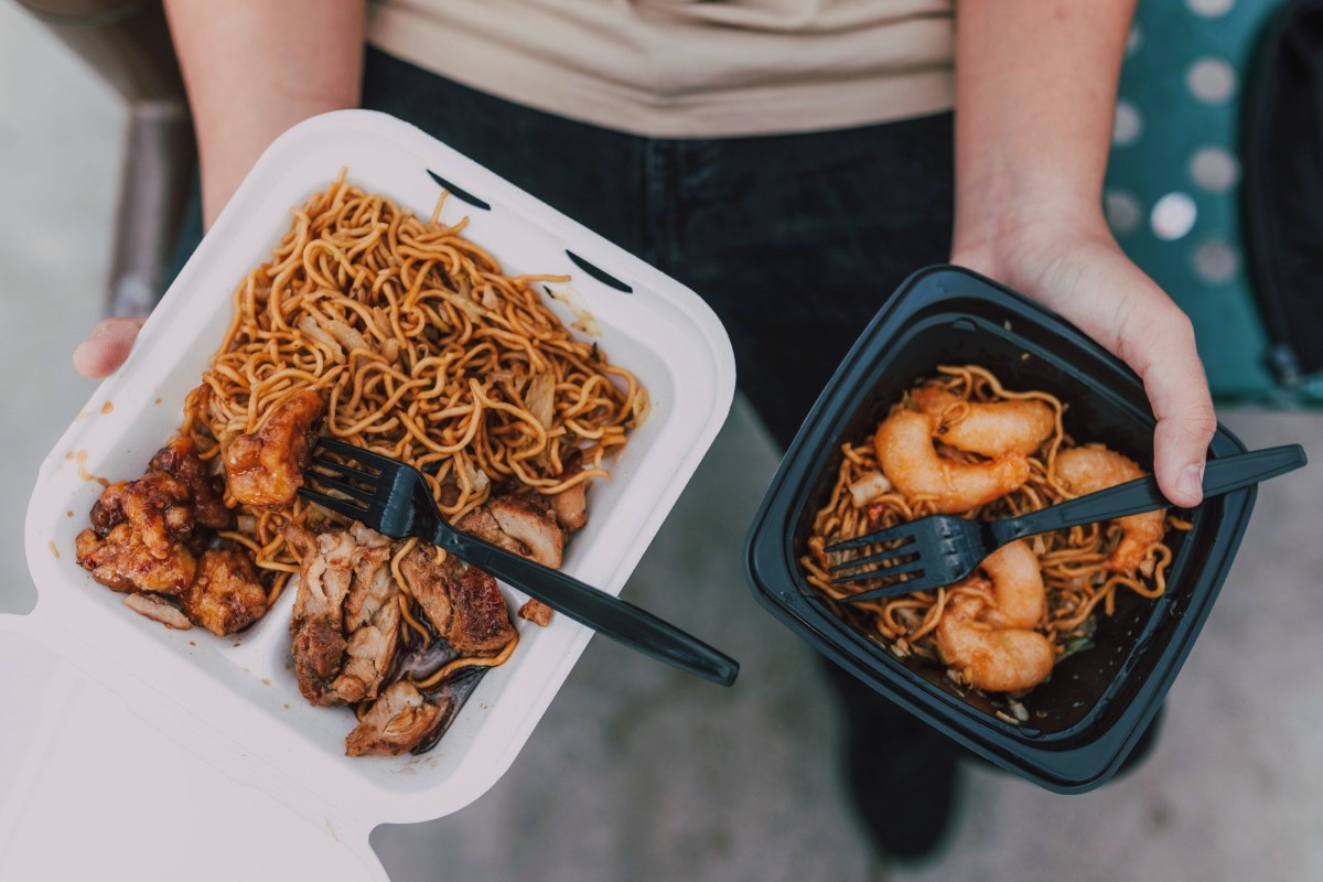 Person's hands holding two containers of food