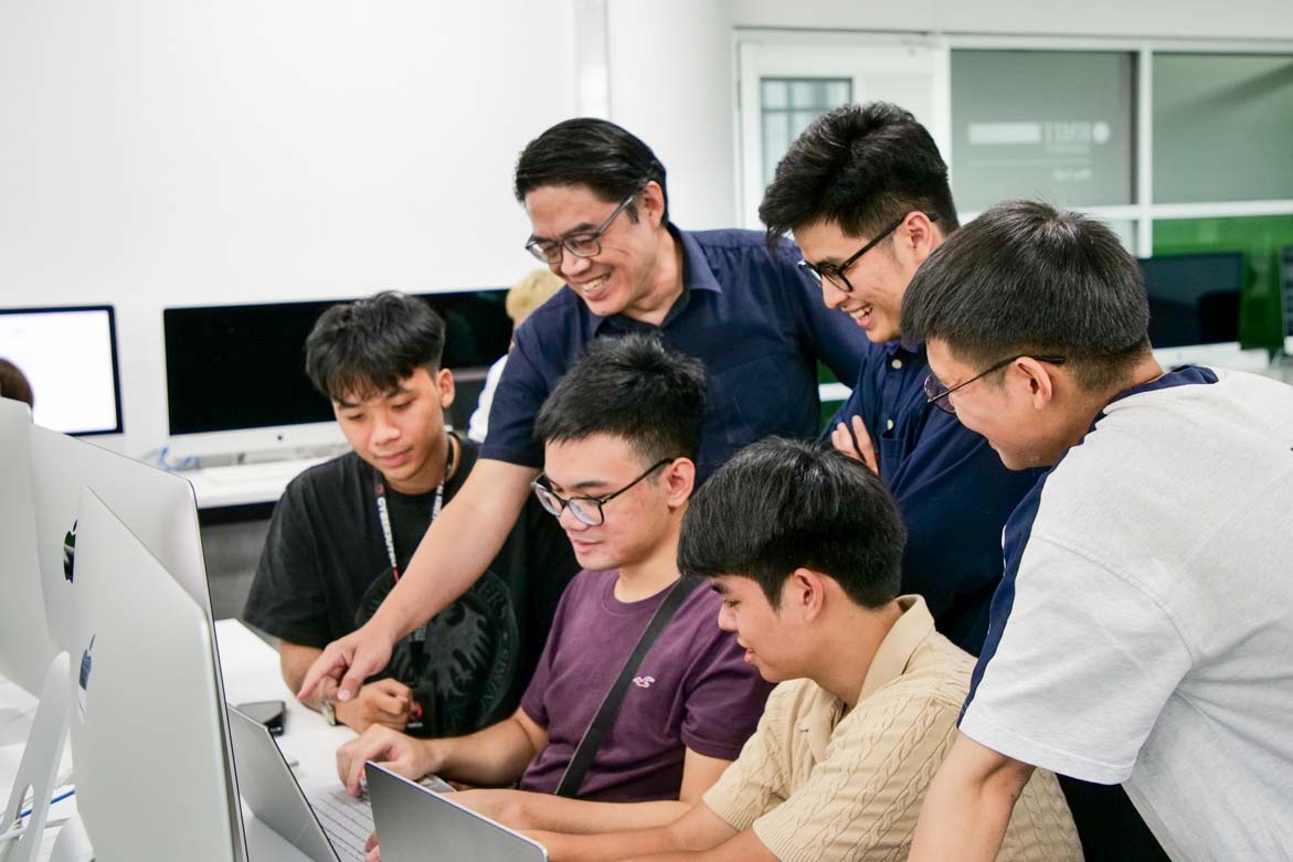 A group of people working together around a laptop.