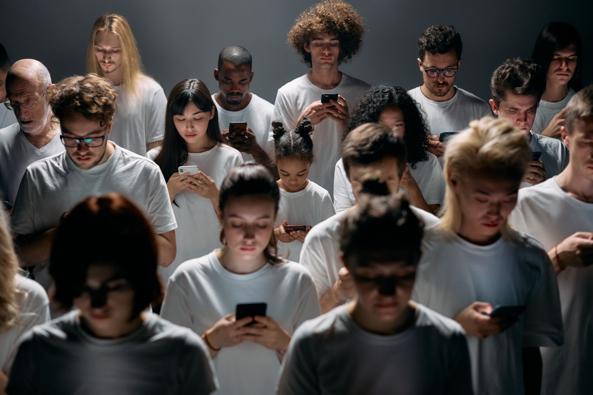 Diverse people in white shirts looking down at their smartphones