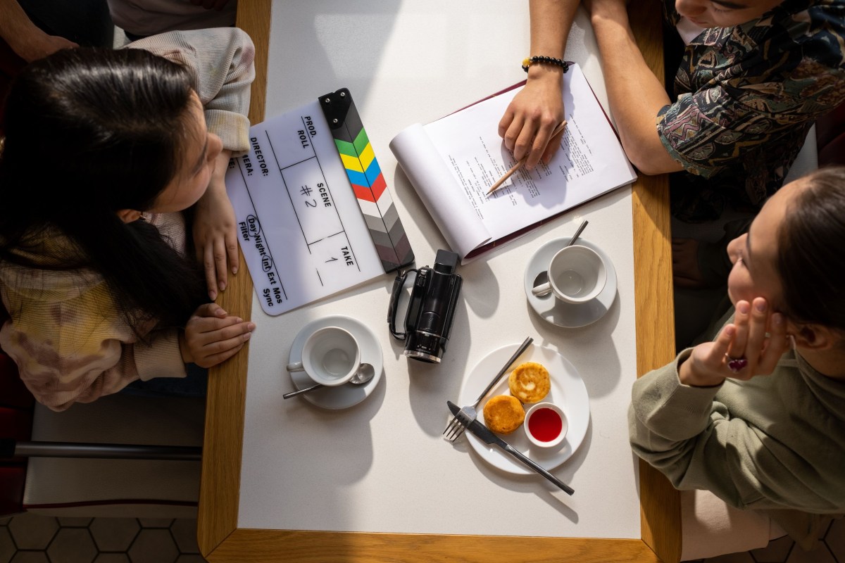 Three people sitting around a table discussing a movie script