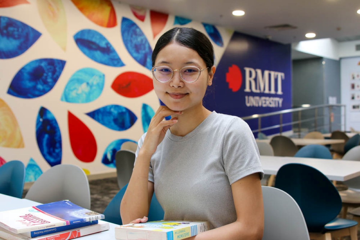 Quynh smiling while sitting at a table