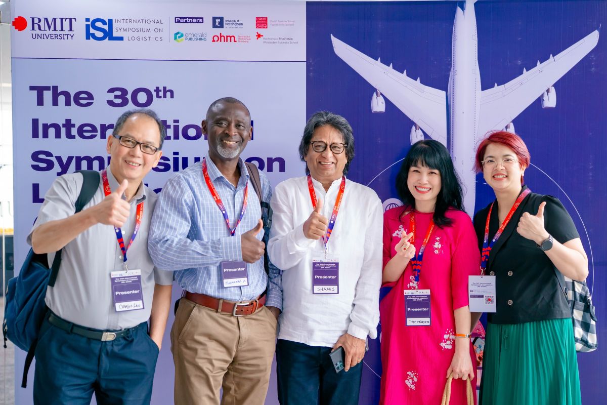 Five people smiling in front of the event backdrop
