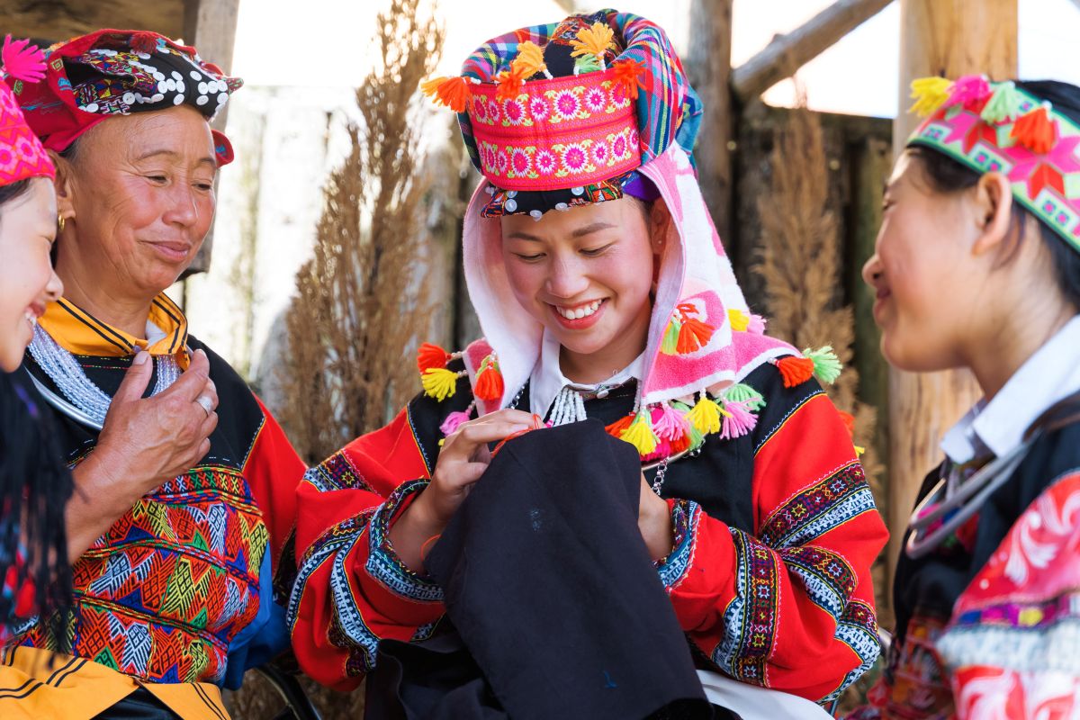 Three women smiling while embroidering