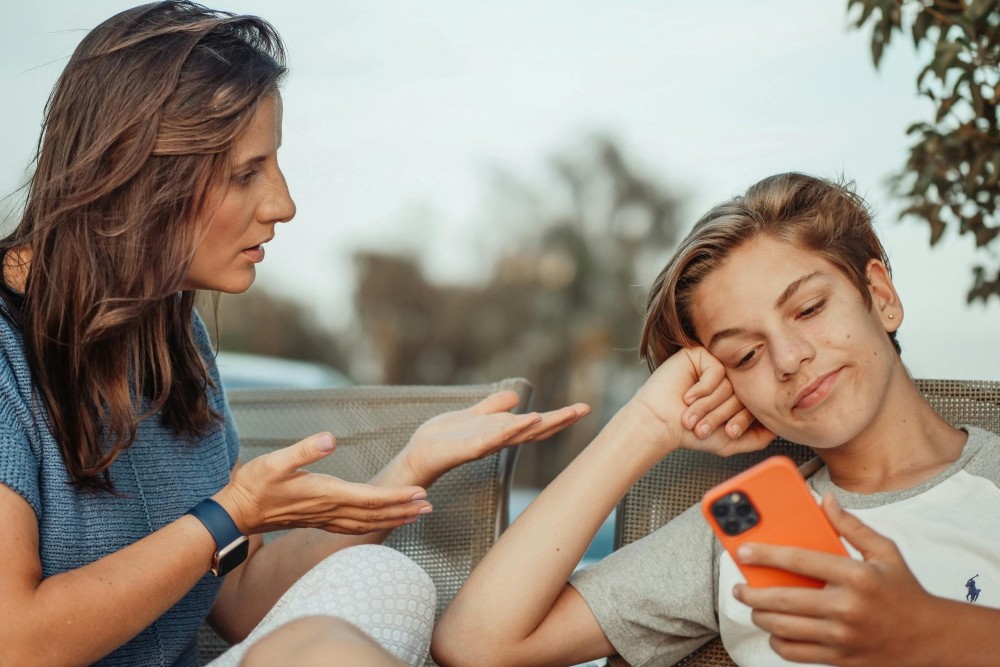 Mother gestures to child who's looking at a smartphone