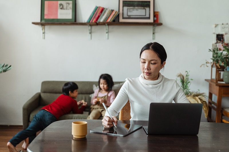 A mother working from home with two kids in the background