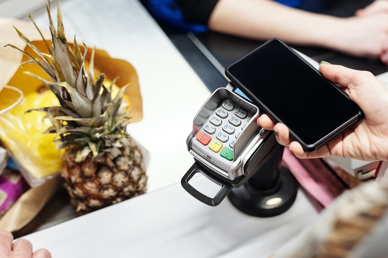 Person paying for groceries with mobile phone NFC function
