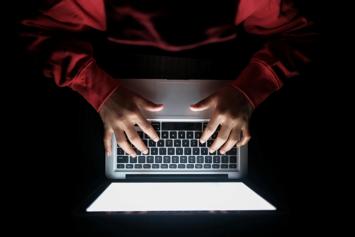 Person typing on computer in the dark