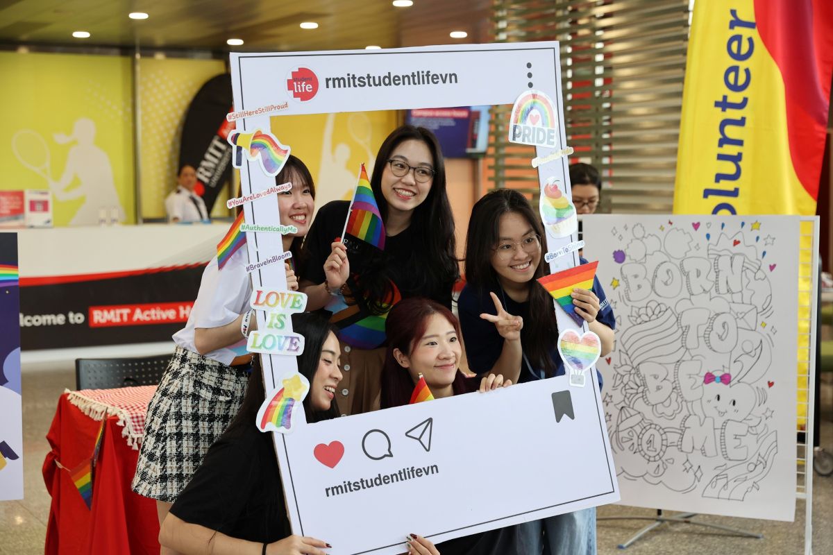 People posing for a photo wwith Pride flags
