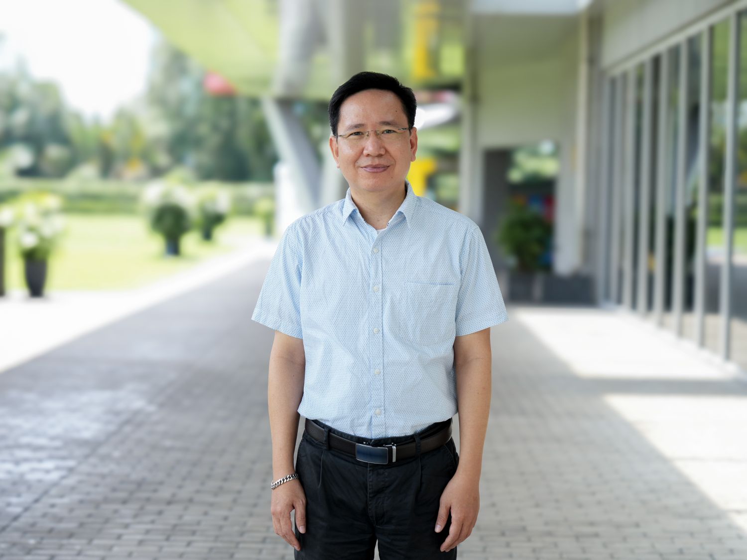 Person standing on a covered walkway beside a modern building.