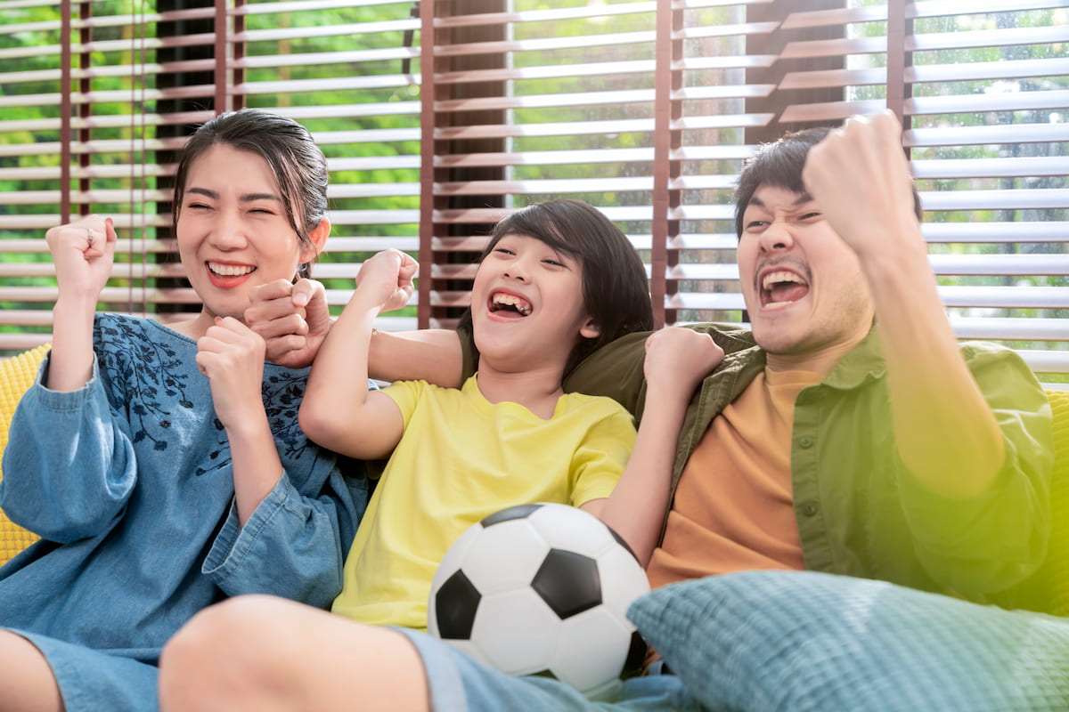 thumbnail-exited-cheerful-joyful-asian-parents-son-watching-sports-tv-cheering-favorite-soccer-team-sitting-together-sofa-couch-home-weekend-with-father-family-time-online-tv-concept.jpg