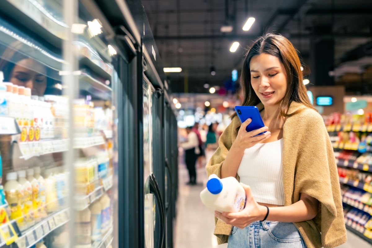 Woman scanning milk jug in supermarket