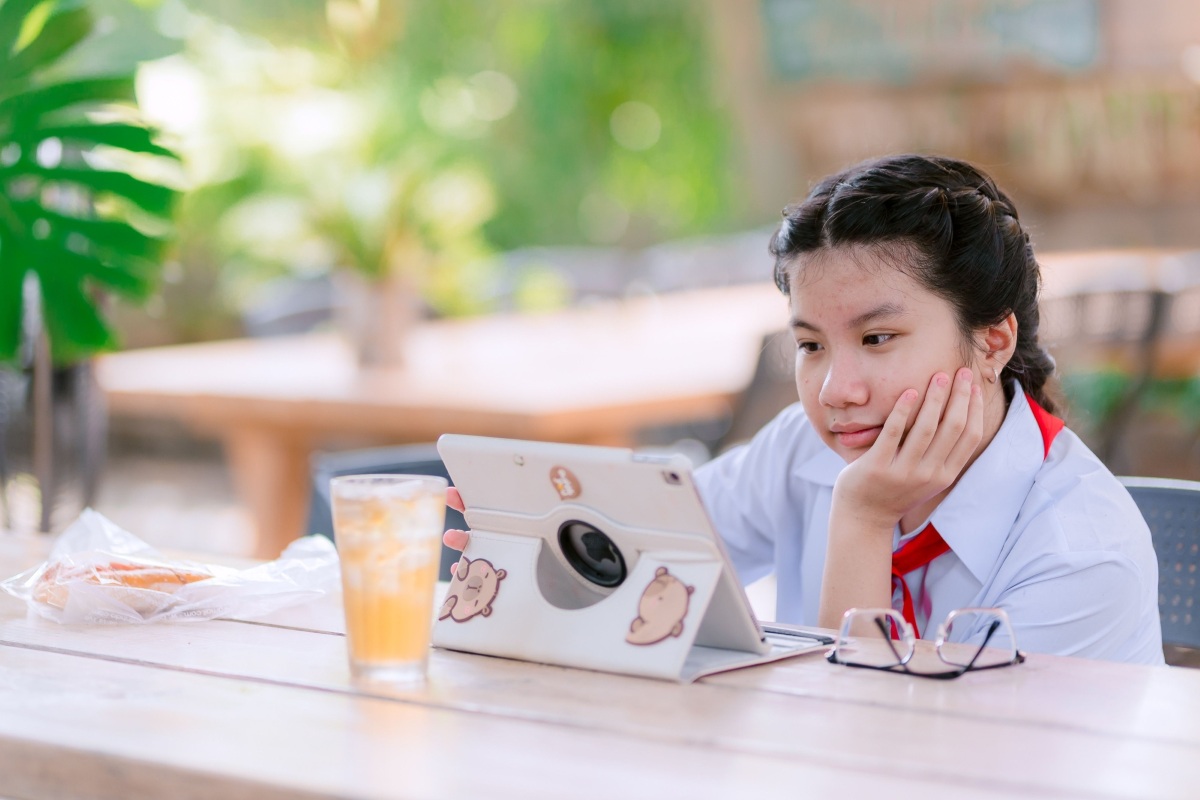 Young girl in school uniform watching a tablet