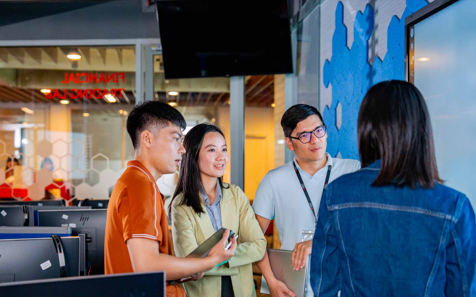 a group of post graduate students discussing in a computer room