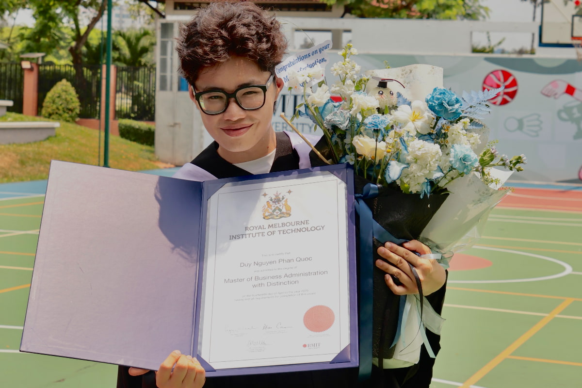 Nguyen Phan Quoc Duy holding MBA degree with Distinction, smiling at camera.