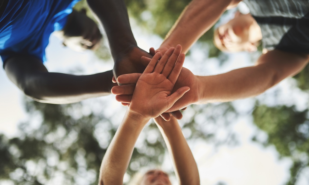 Low angle shot of people holding their hands together in unity.