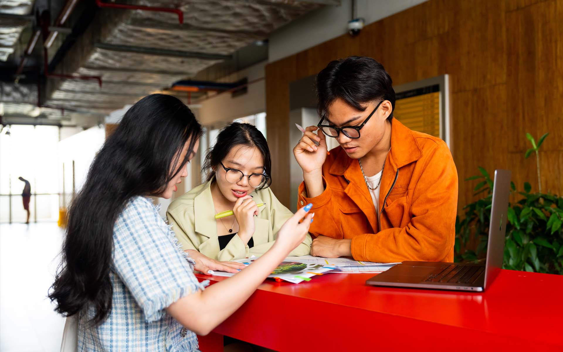 three students one male and two female working on campus