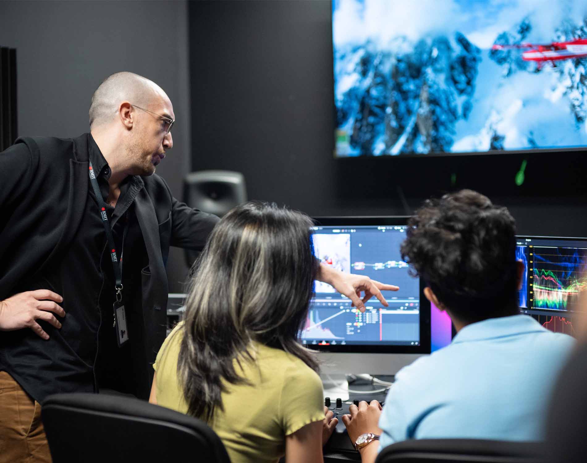 teacher pointing at screen in front of two students