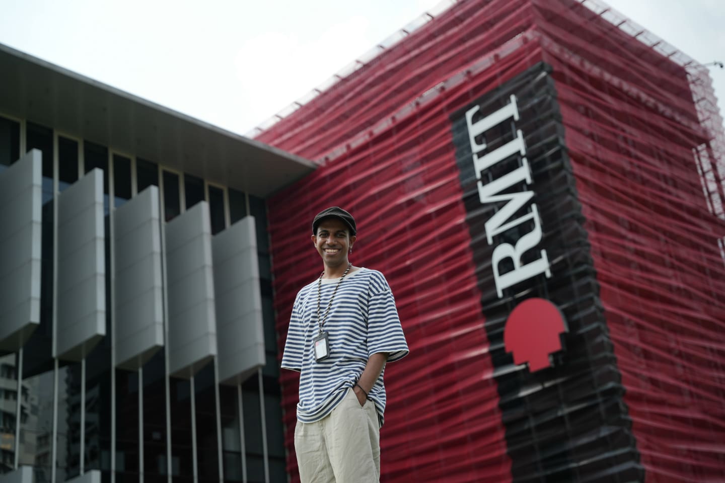 Photo of Saurabh Padmakumar an RMIT Vietnam's student holding a laptop case smiling in front of building two at RMIT Saigon South campus.