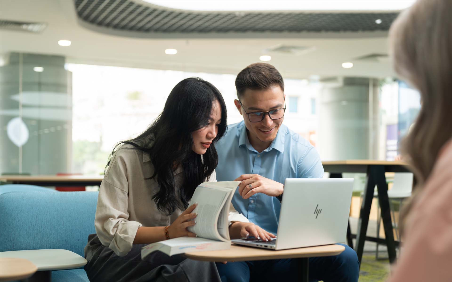 a female student and a male lecturer working on laptop together