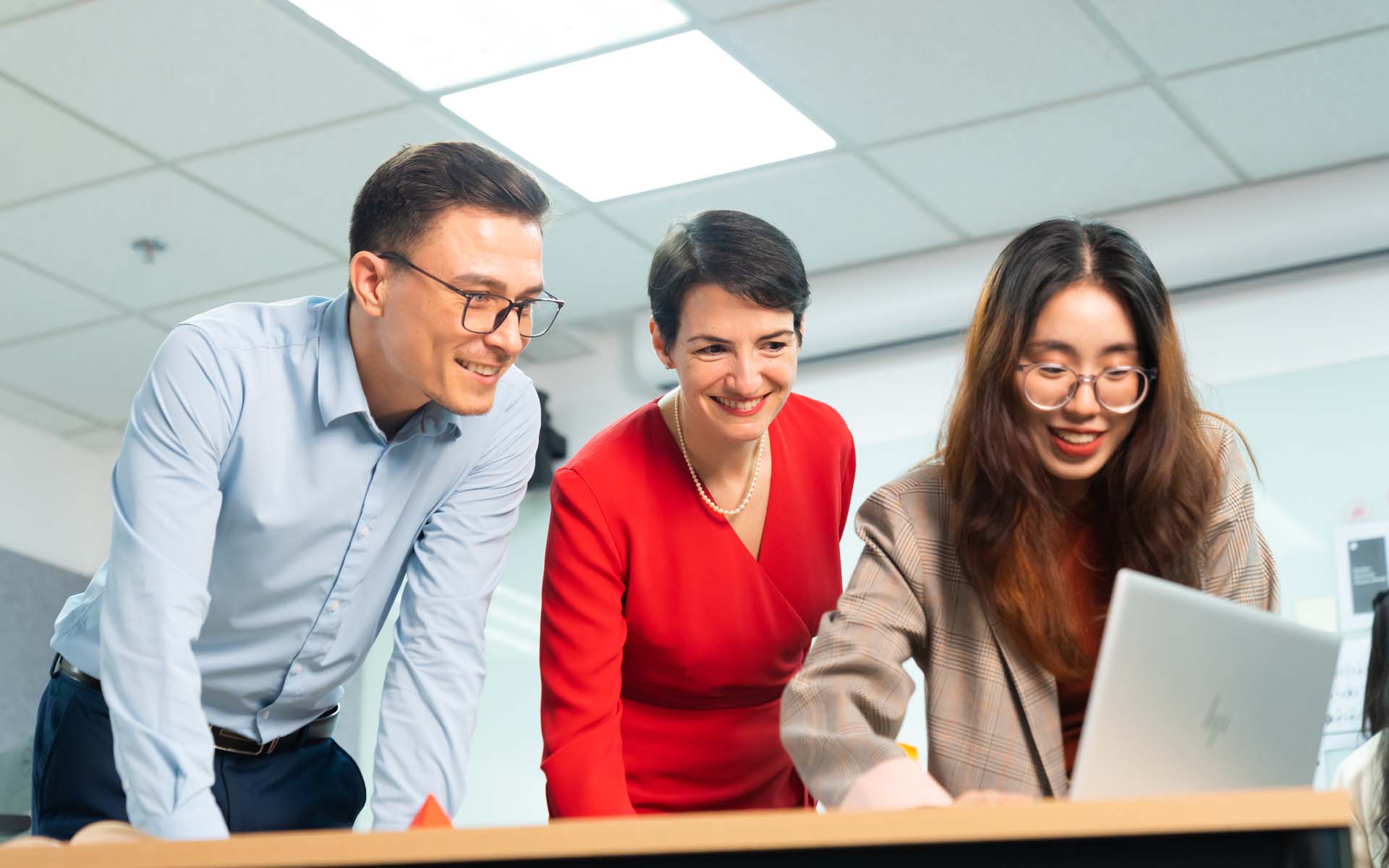 two lecturers and one student discussing over a laptop