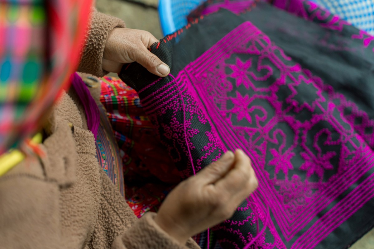 Close-up of a person weaving traditional fabric.