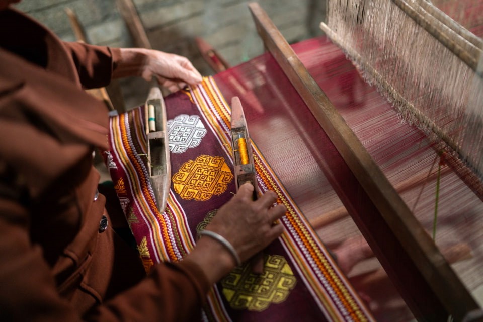 Close-up of a person weaving traditional fabric on a loom.