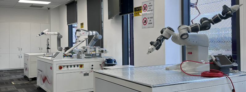 Photo of a robotics lab at RMIT Vietnam featuring three ABB branded robots.