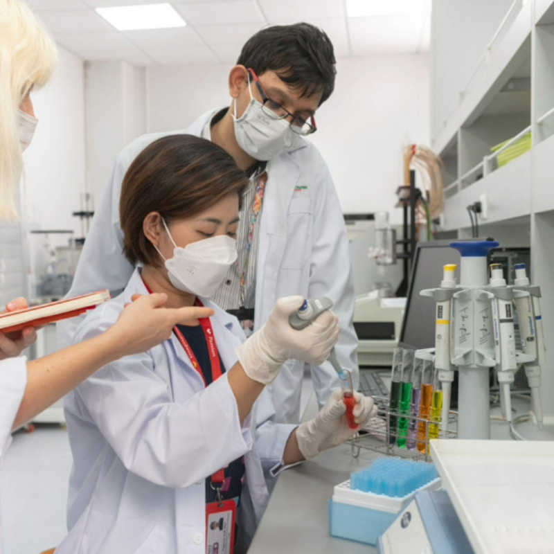 Photo of students and researchers in a laboratory environment conducting experiments with test tubes and pipettes, indicating teamwork and collaboration in scientific research or experimentation.