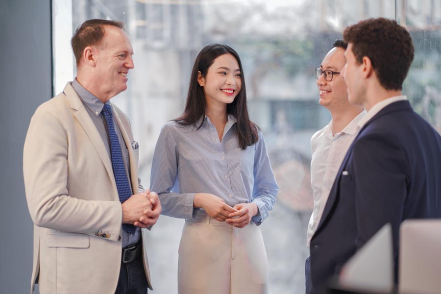 Photo of a group of 4 professionals in business attires smiling and discussing with each othe