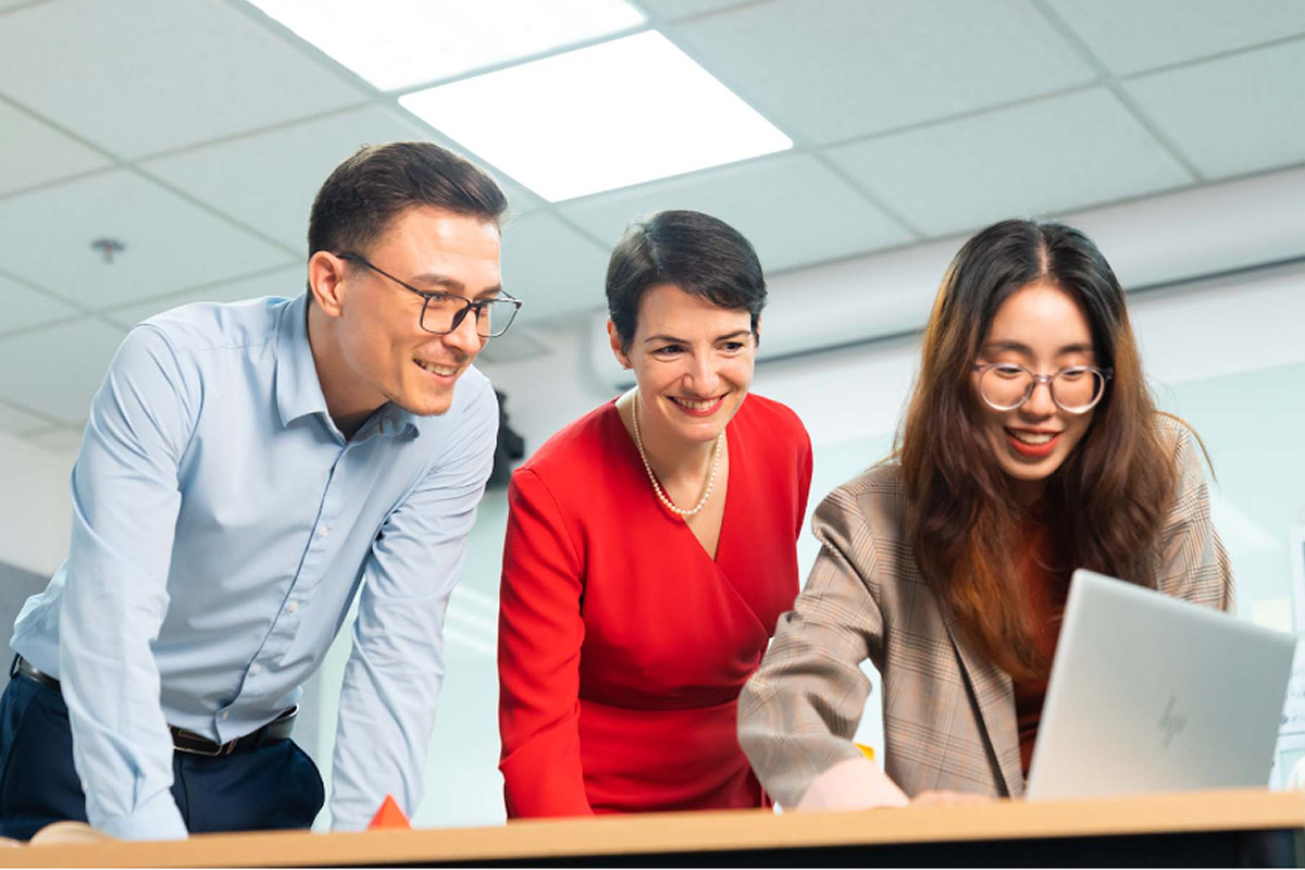 Một nữ sinh vien đang trình bày với hai giảng viên trên thiết bị máy tính laptop