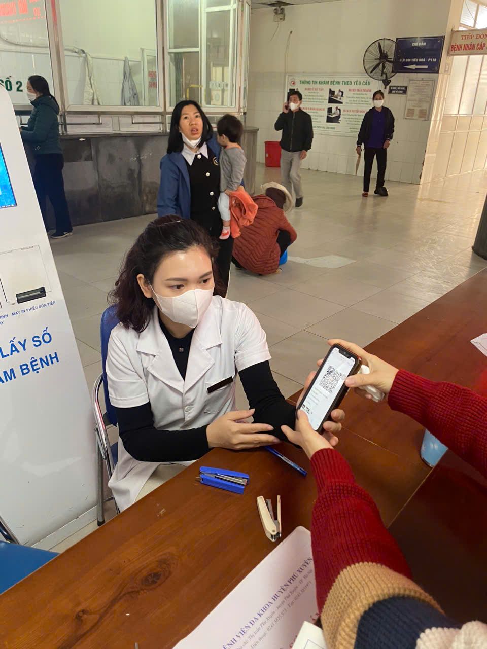 A healthcare worker in front of digital kiosk assisting patients