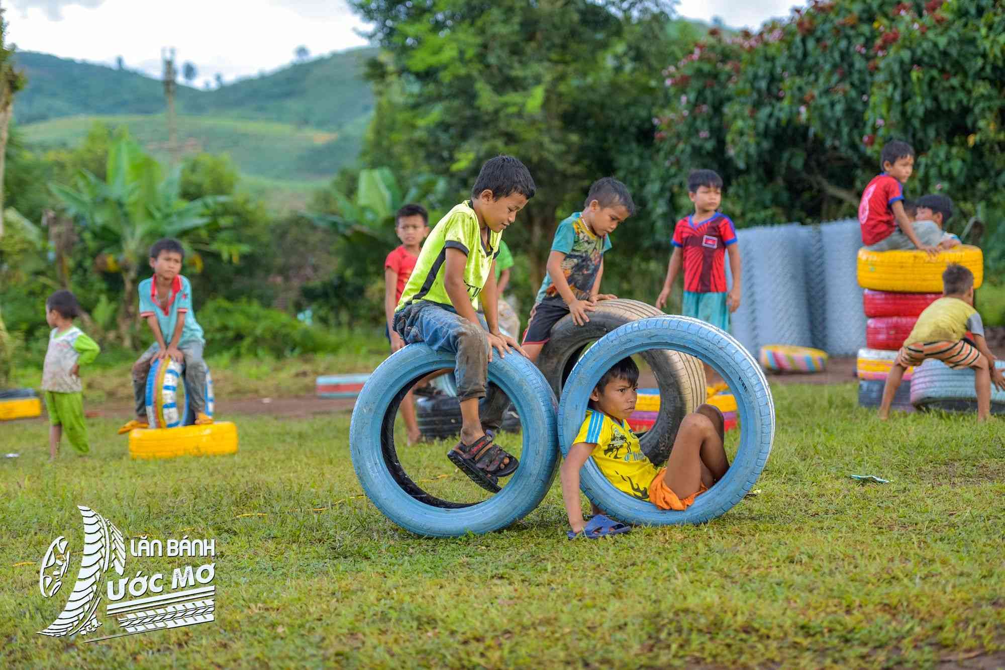 Children playing with recycled tyre structures at a Wheel of dreams playground