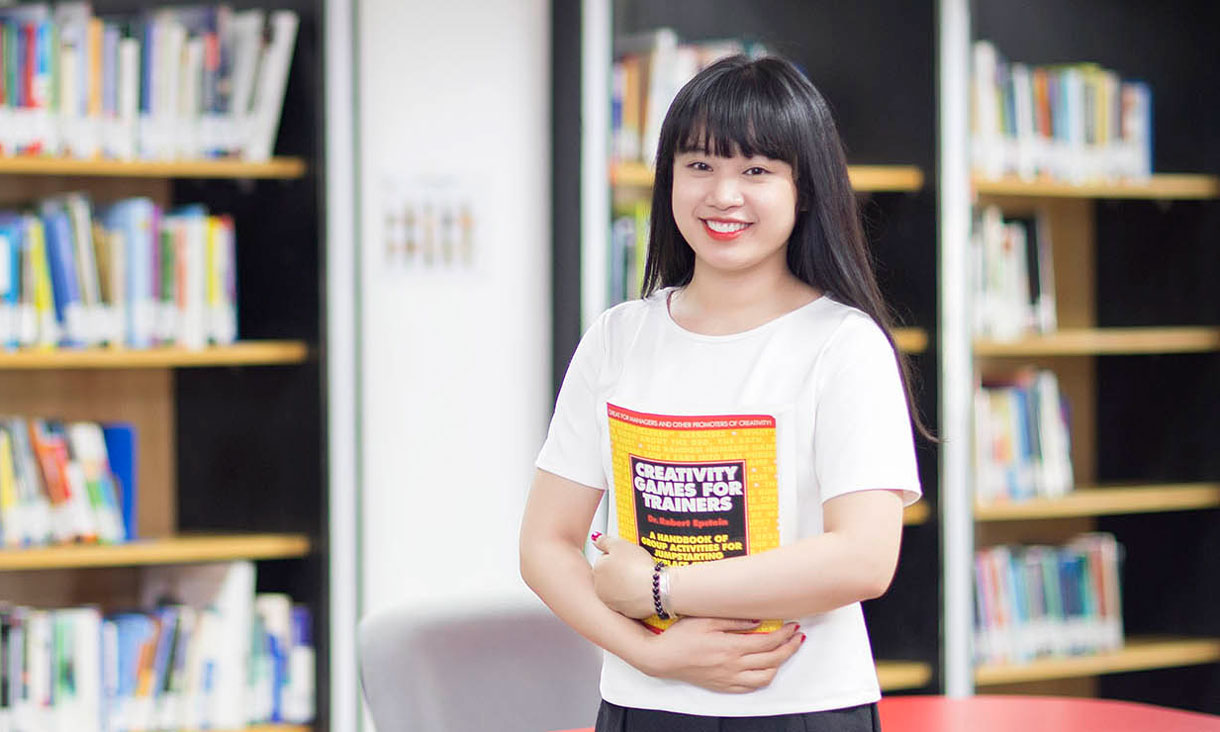 female student holding a book looking at the camera