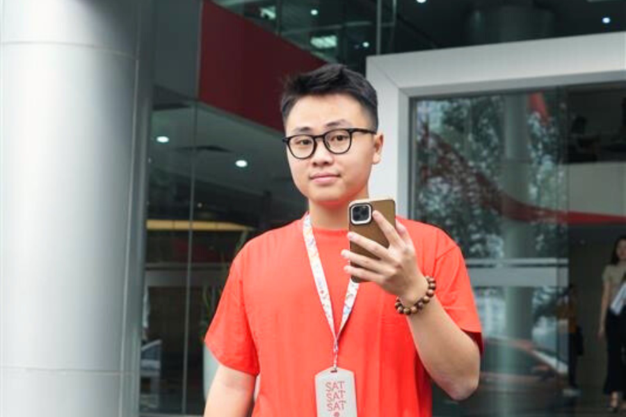 A young man in a red shirt holding a cell phone.