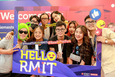 nine students stand behind a photo frame said hello rmit