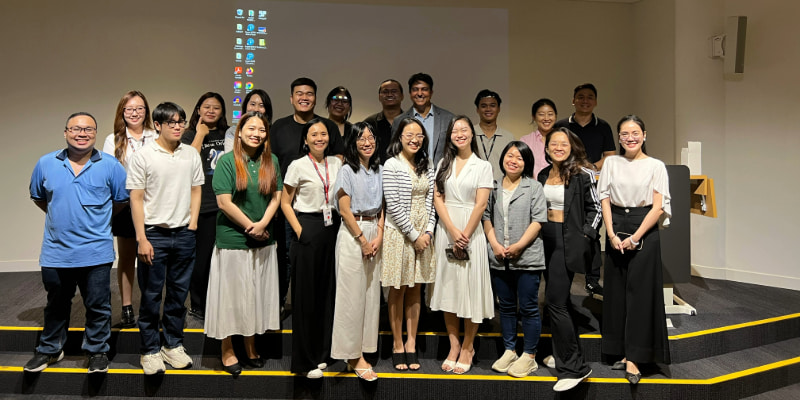 Photo of a group of postgraduate students and a guest lecturer smiling in front of the auditorium at RMIT Vietnam