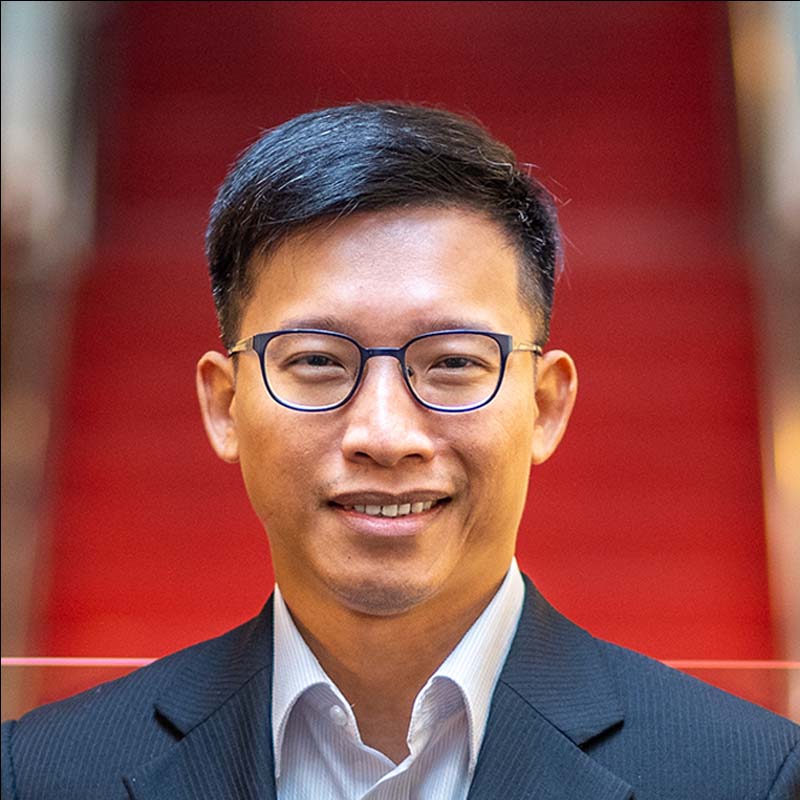 a headshot of an asian man in suit smiling 