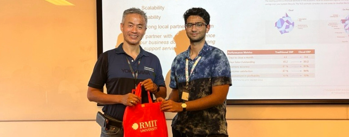 Photo of a guest lecturer being gifted an RMIT branded gift bag by a postgraduate student in front of the class